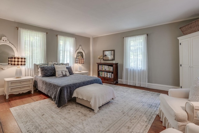 bedroom with baseboards, ornamental molding, and wood finished floors