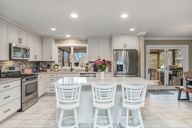 kitchen featuring marble finish floor, a wealth of natural light, ornamental molding, and stainless steel appliances