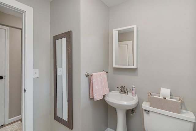 bathroom with toilet, a sink, and baseboards