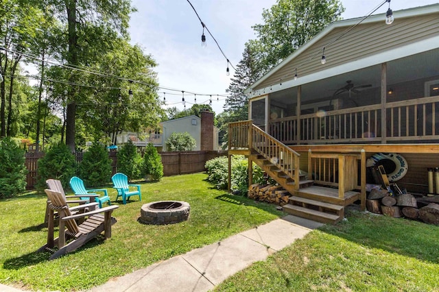 view of yard featuring fence, a ceiling fan, stairs, a sunroom, and an outdoor fire pit