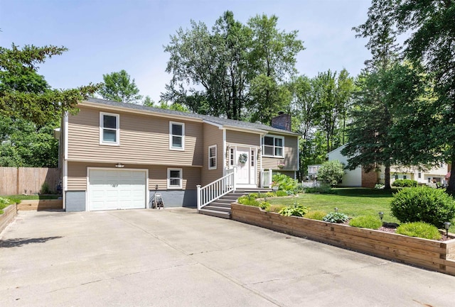 split foyer home featuring a chimney, a front lawn, driveway, an attached garage, and fence