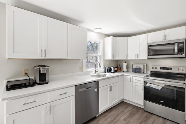 kitchen with appliances with stainless steel finishes, a sink, and white cabinetry