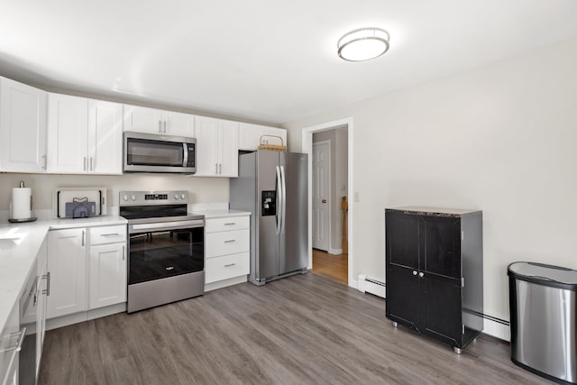 kitchen with a baseboard heating unit, white cabinets, stainless steel appliances, and light wood-style floors