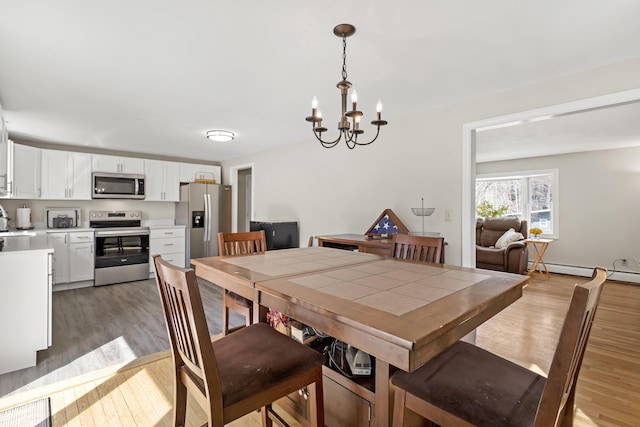 dining space with light wood-style floors, a chandelier, and a baseboard radiator