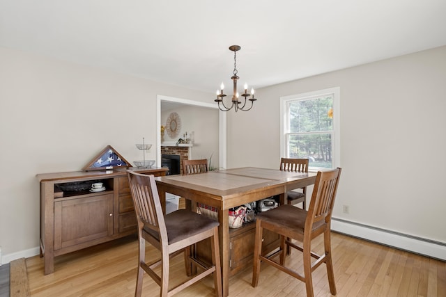 dining space with a baseboard heating unit, a chandelier, light wood-type flooring, and baseboards