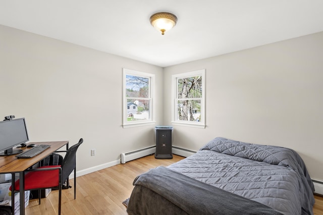 bedroom featuring a baseboard heating unit, baseboards, and light wood finished floors