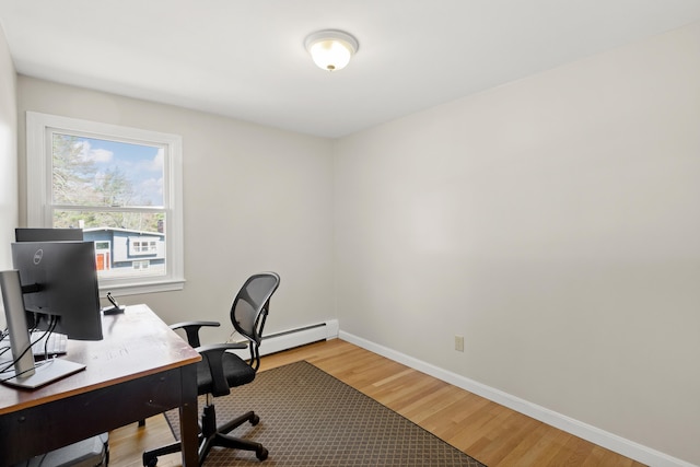 home office with light wood-type flooring, baseboard heating, and baseboards