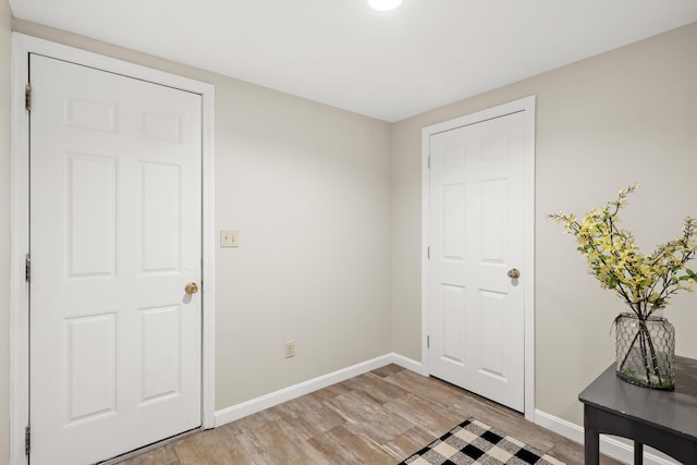 interior space featuring baseboards and light wood finished floors
