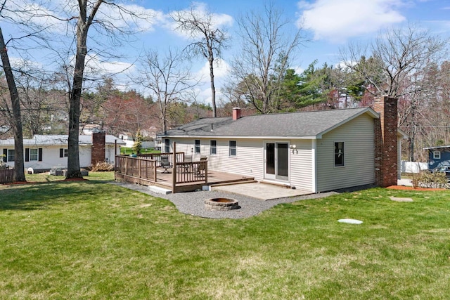 rear view of house featuring a wooden deck, a lawn, a fire pit, and a chimney