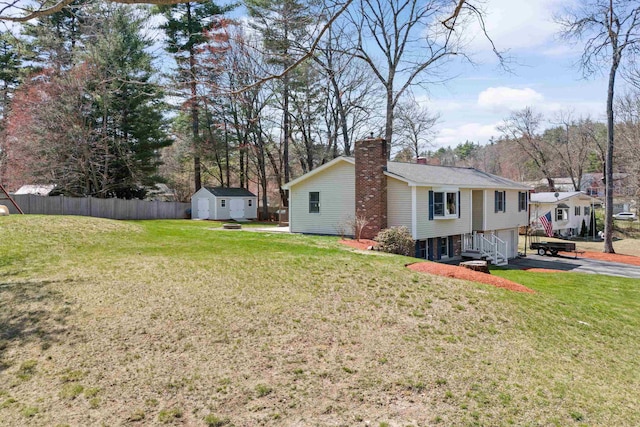 view of home's exterior featuring a storage shed, a chimney, fence, a lawn, and an outdoor structure