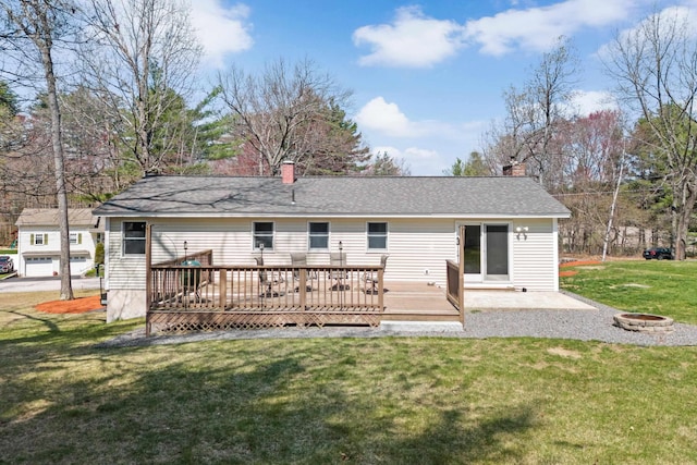 back of house with a chimney, a wooden deck, a yard, a patio, and an outdoor fire pit