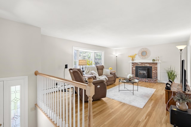 living room with light wood-style flooring and a brick fireplace