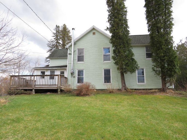 rear view of property with a yard, roof with shingles, and a deck
