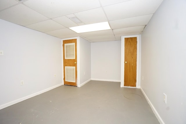 empty room featuring a paneled ceiling, visible vents, finished concrete flooring, and baseboards
