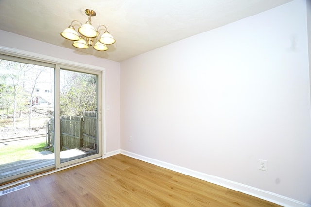 unfurnished dining area with visible vents, baseboards, an inviting chandelier, and light wood-style floors