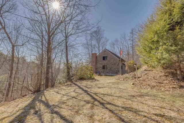 view of property exterior with an outbuilding, a barn, and a chimney
