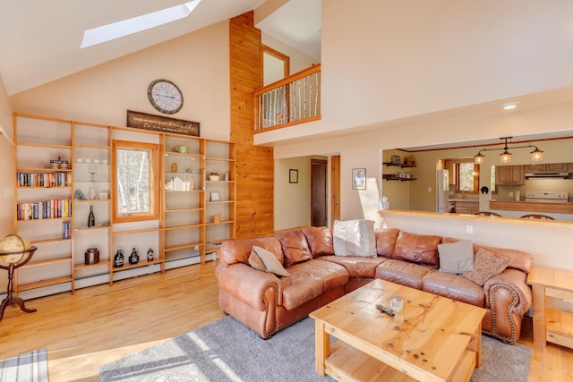 living room featuring a skylight, wood finished floors, and high vaulted ceiling