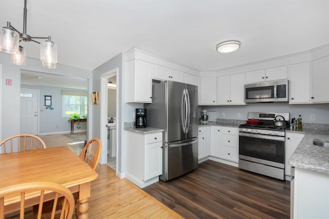 kitchen with stainless steel appliances, white cabinetry, baseboards, dark wood-style flooring, and light stone countertops