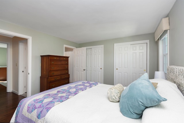 bedroom with baseboards, multiple closets, and dark wood-style floors