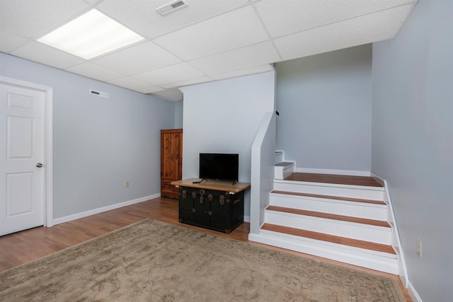 interior space with wood finished floors, visible vents, a drop ceiling, and baseboards