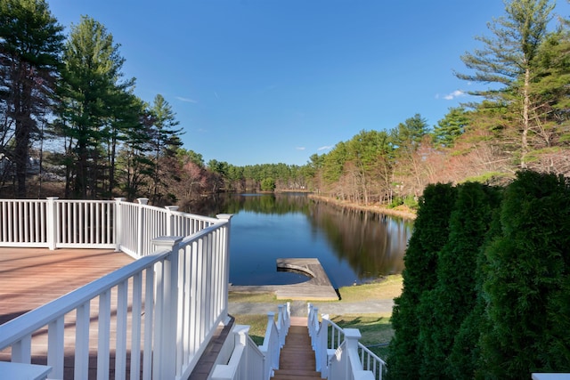 view of dock with a wooded view and a water view