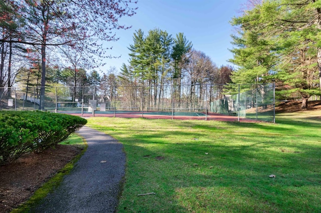 view of property's community with a lawn, fence, and a tennis court