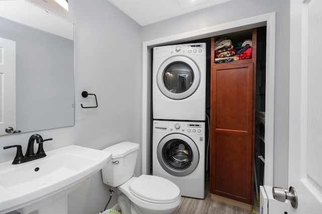 half bath featuring stacked washer / drying machine, toilet, and a sink