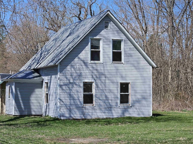 view of side of home with a lawn and metal roof