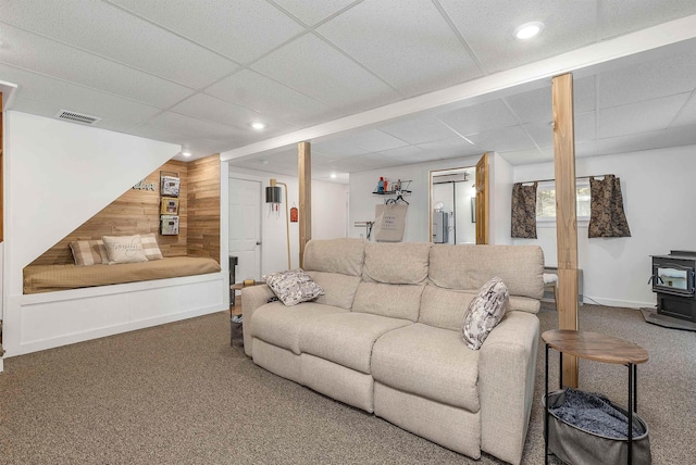 living area with wooden walls, a wood stove, carpet, visible vents, and recessed lighting