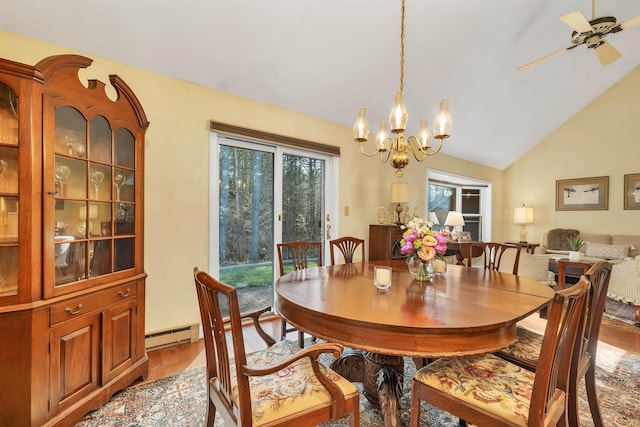 dining room with vaulted ceiling, wood finished floors, ceiling fan with notable chandelier, and a baseboard radiator