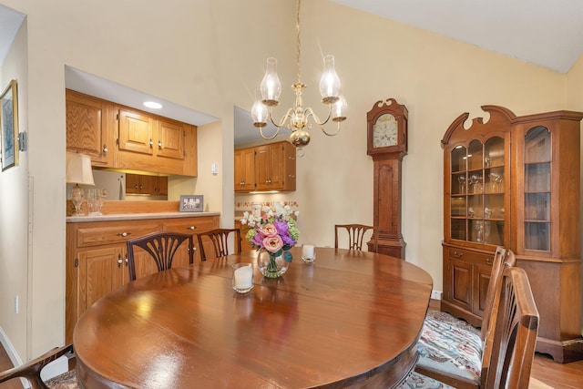 dining space with baseboards, high vaulted ceiling, an inviting chandelier, and light wood-style flooring