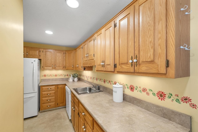 kitchen featuring recessed lighting, white appliances, light countertops, and a sink