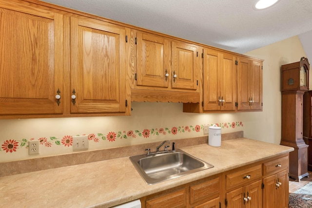 kitchen with brown cabinetry, light countertops, and a sink