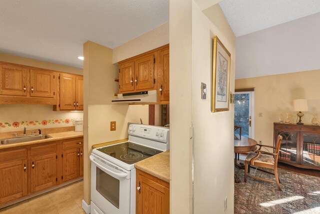 kitchen featuring a sink, under cabinet range hood, light countertops, and white range with electric stovetop
