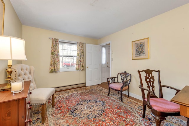 sitting room with a baseboard radiator, wood finished floors, and baseboards