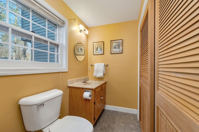 bathroom with baseboards, toilet, a closet, and vanity