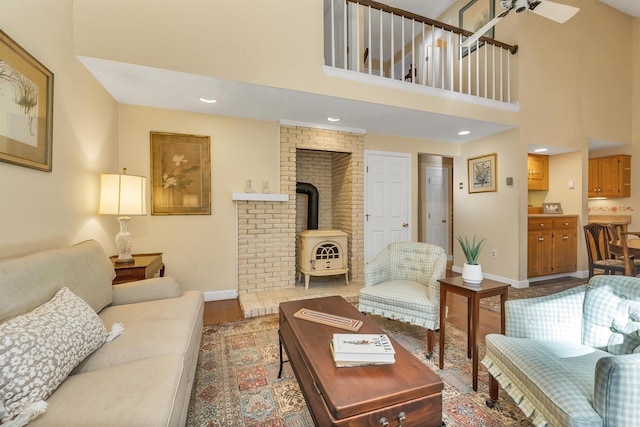 living area with wood finished floors, a high ceiling, a wood stove, and baseboards