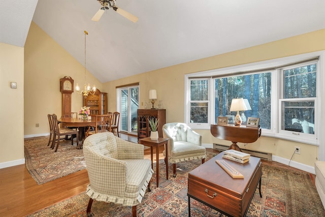 living area featuring baseboards, wood finished floors, a baseboard heating unit, and ceiling fan with notable chandelier