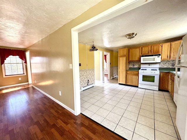 207 Blakely Farm Rd, Colebrook, NH 03576 - kitchen featuring white appliances, a textured ceiling, brown cabinets, and a baseboard radiator