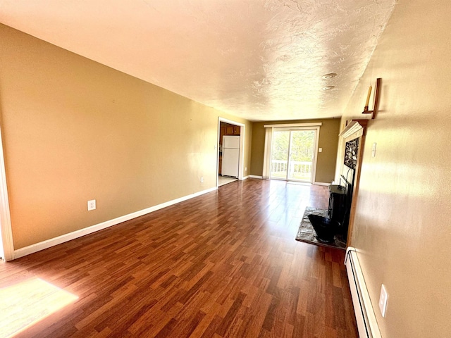 207 Blakely Farm Rd, Colebrook, NH 03576 - unfurnished living room with a wood stove, dark wood-style flooring, baseboards, a textured ceiling, and baseboard heating