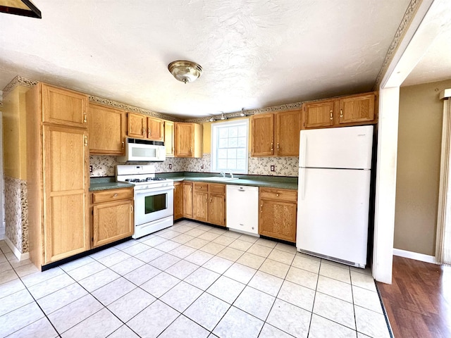 207 Blakely Farm Rd, Colebrook, NH 03576 - kitchen with baseboards, dark countertops, white appliances, and a sink