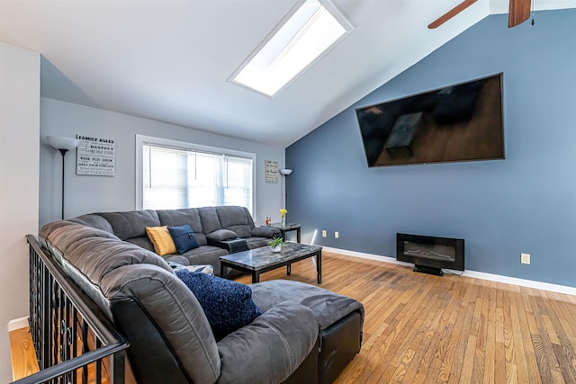 living area with hardwood / wood-style floors, ceiling fan, vaulted ceiling, and baseboards