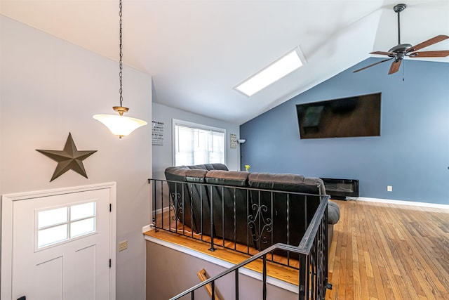 interior space featuring wood-type flooring, a ceiling fan, lofted ceiling, and baseboards