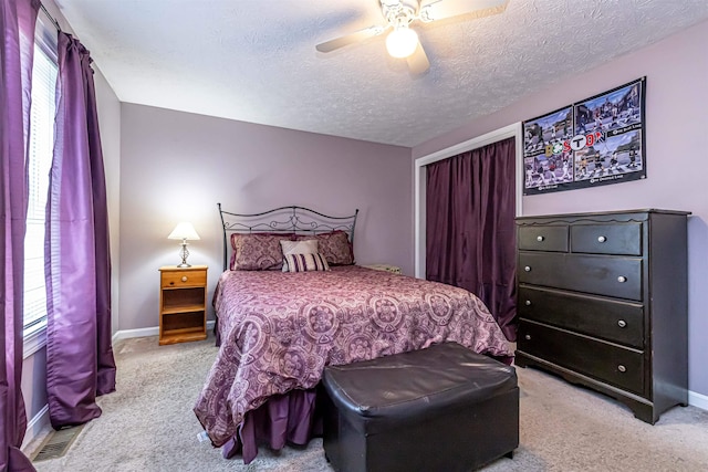 bedroom featuring light colored carpet, baseboards, and a textured ceiling