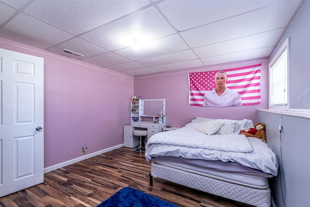 bedroom with visible vents, a drop ceiling, wood finished floors, and baseboards