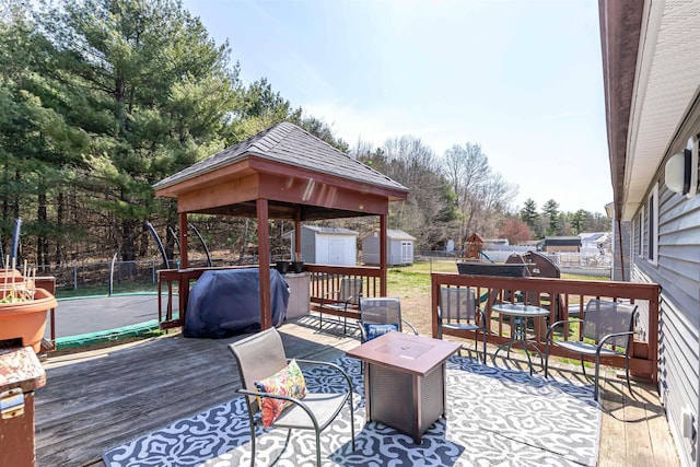 wooden terrace with an outdoor structure, fence, a gazebo, a storage shed, and area for grilling