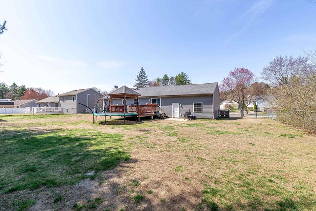 back of house with a trampoline, a gazebo, a deck, fence, and a yard