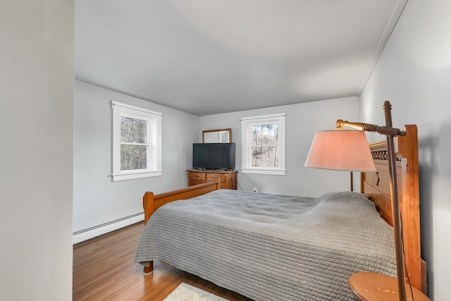 bedroom with wood finished floors and a baseboard radiator