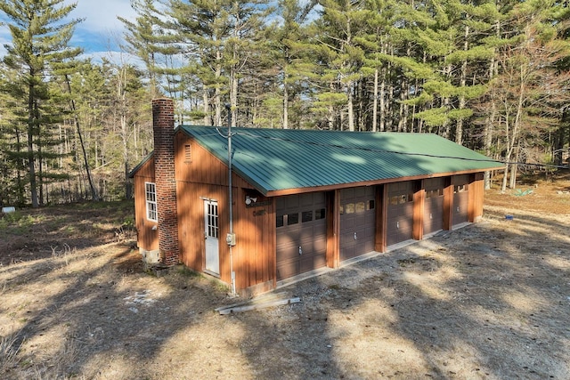 detached garage with a view of trees