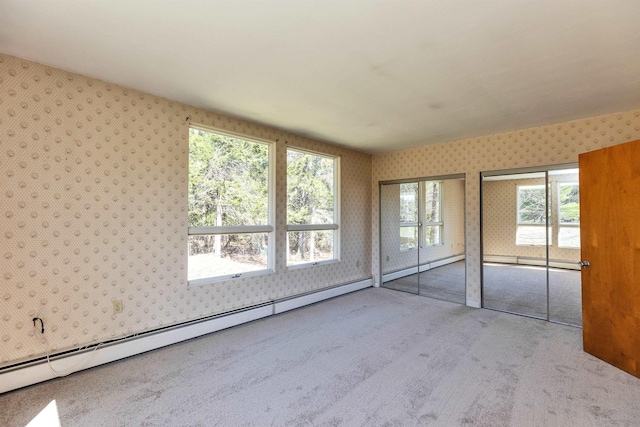 unfurnished bedroom with a baseboard radiator, carpet, multiple closets, and wallpapered walls